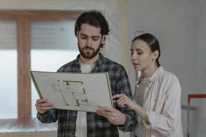 A man and a woman are looking at a floor plan of a house.