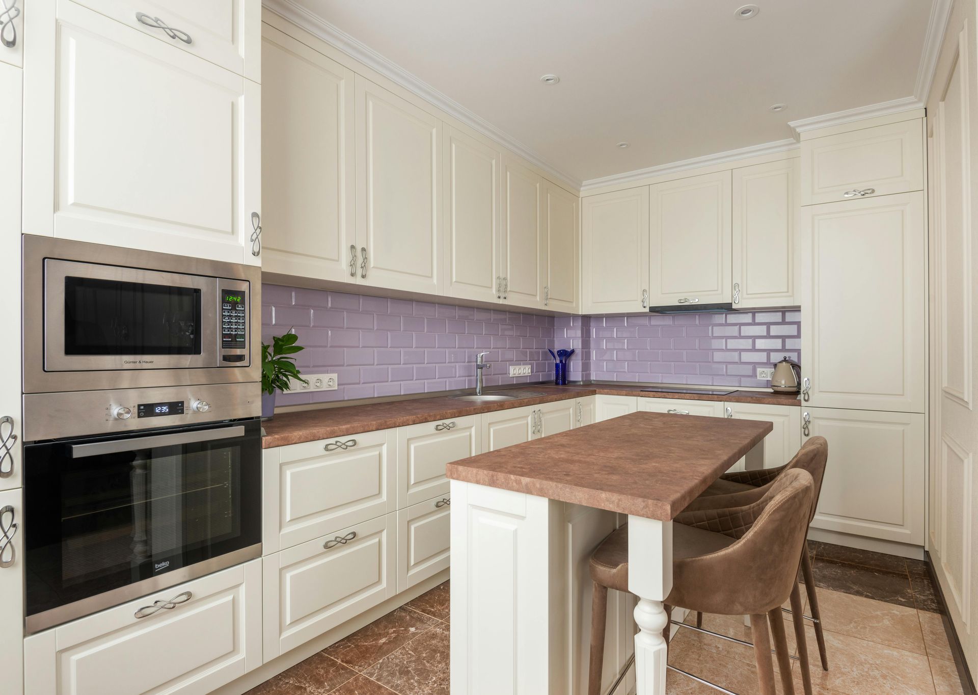 A kitchen with white cabinets , a stove , a sink and a brick wall.