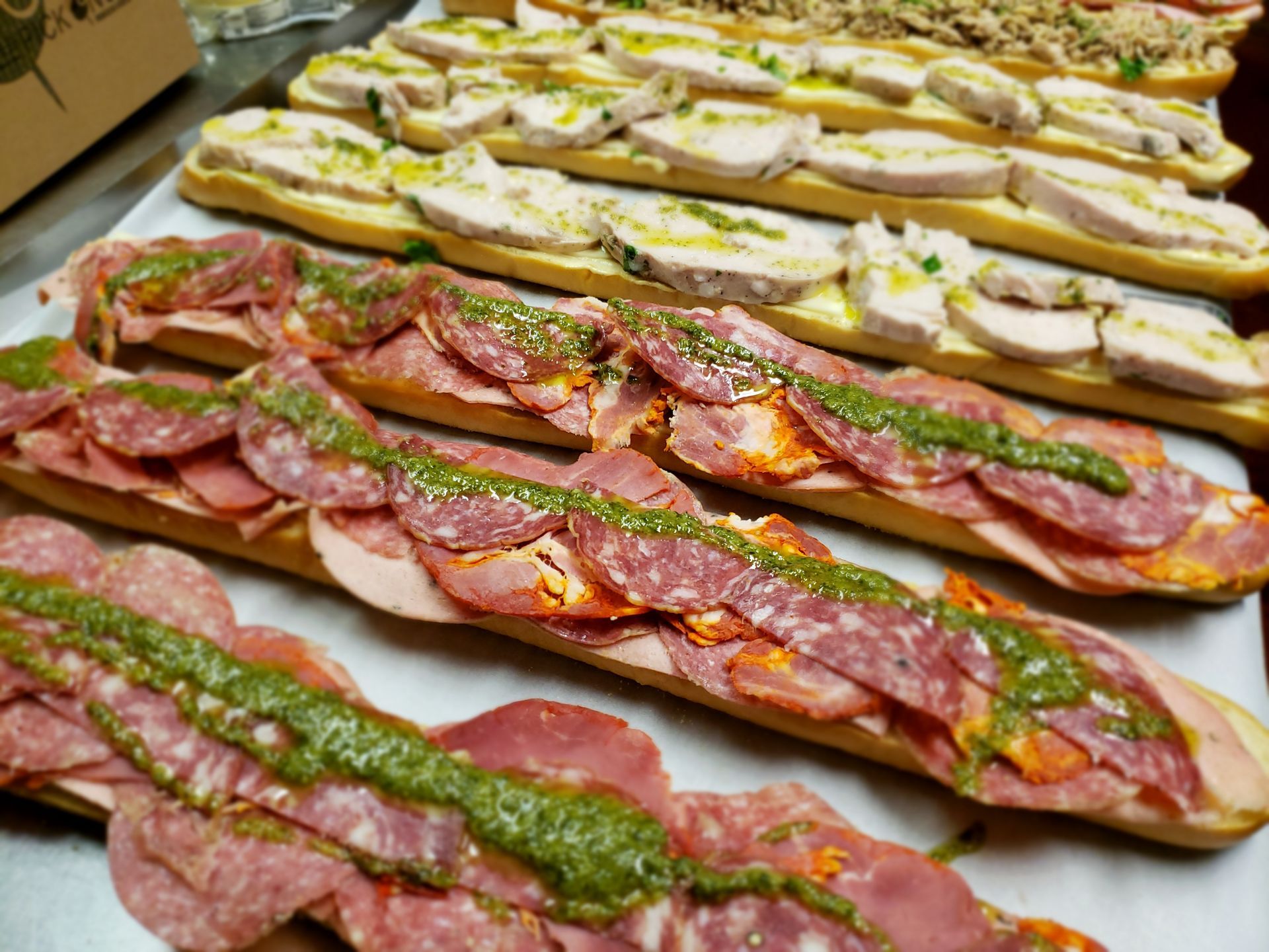 Long bread loaves filled with sliced meats and pesto.