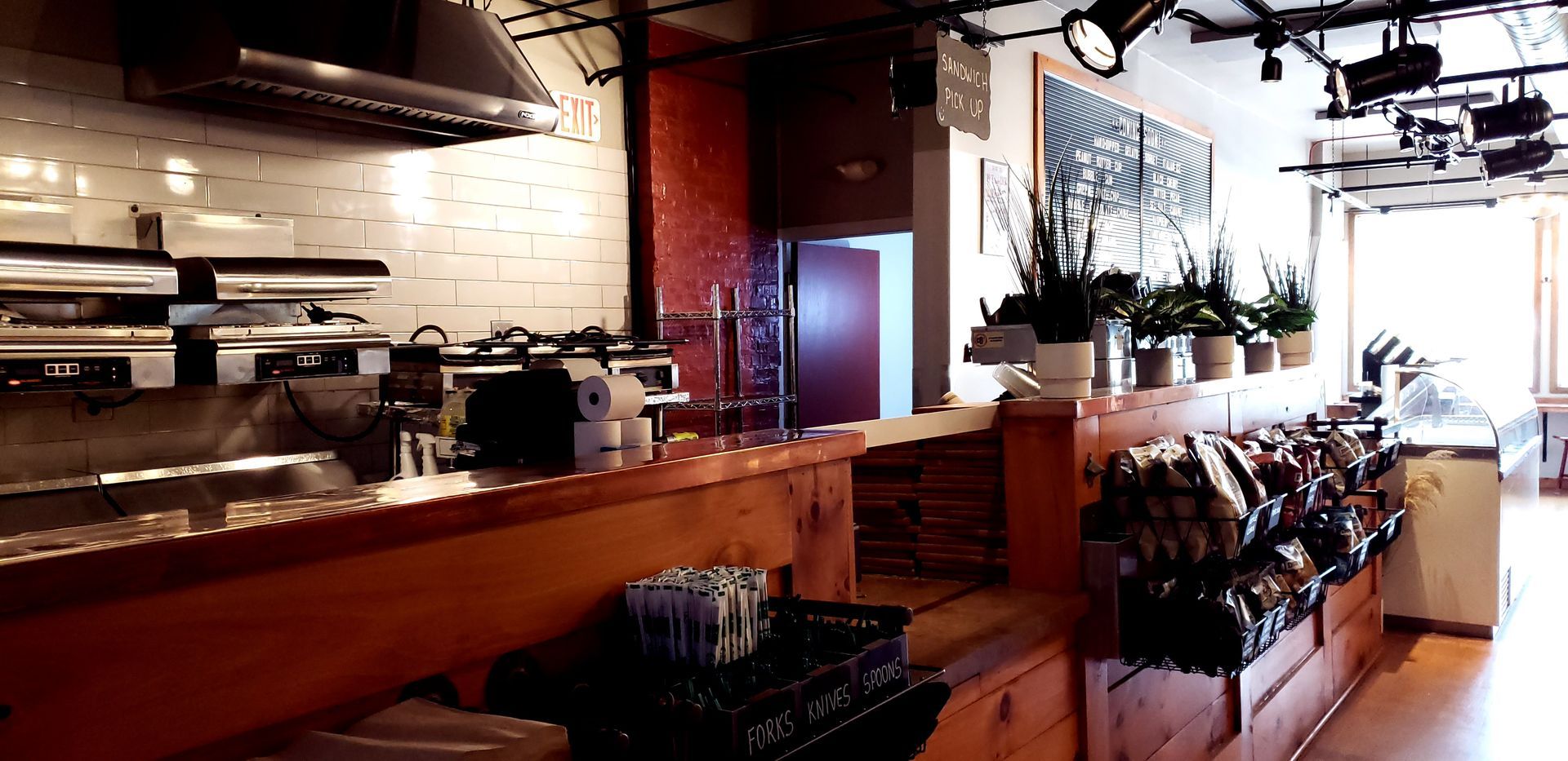 Interior of a cafe with a counter, plants, and food displayed.