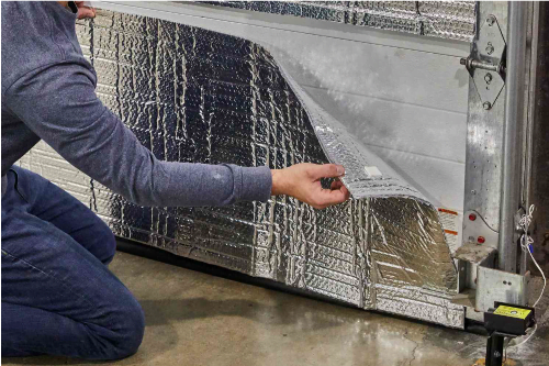 A man is installing insulation on a garage door.