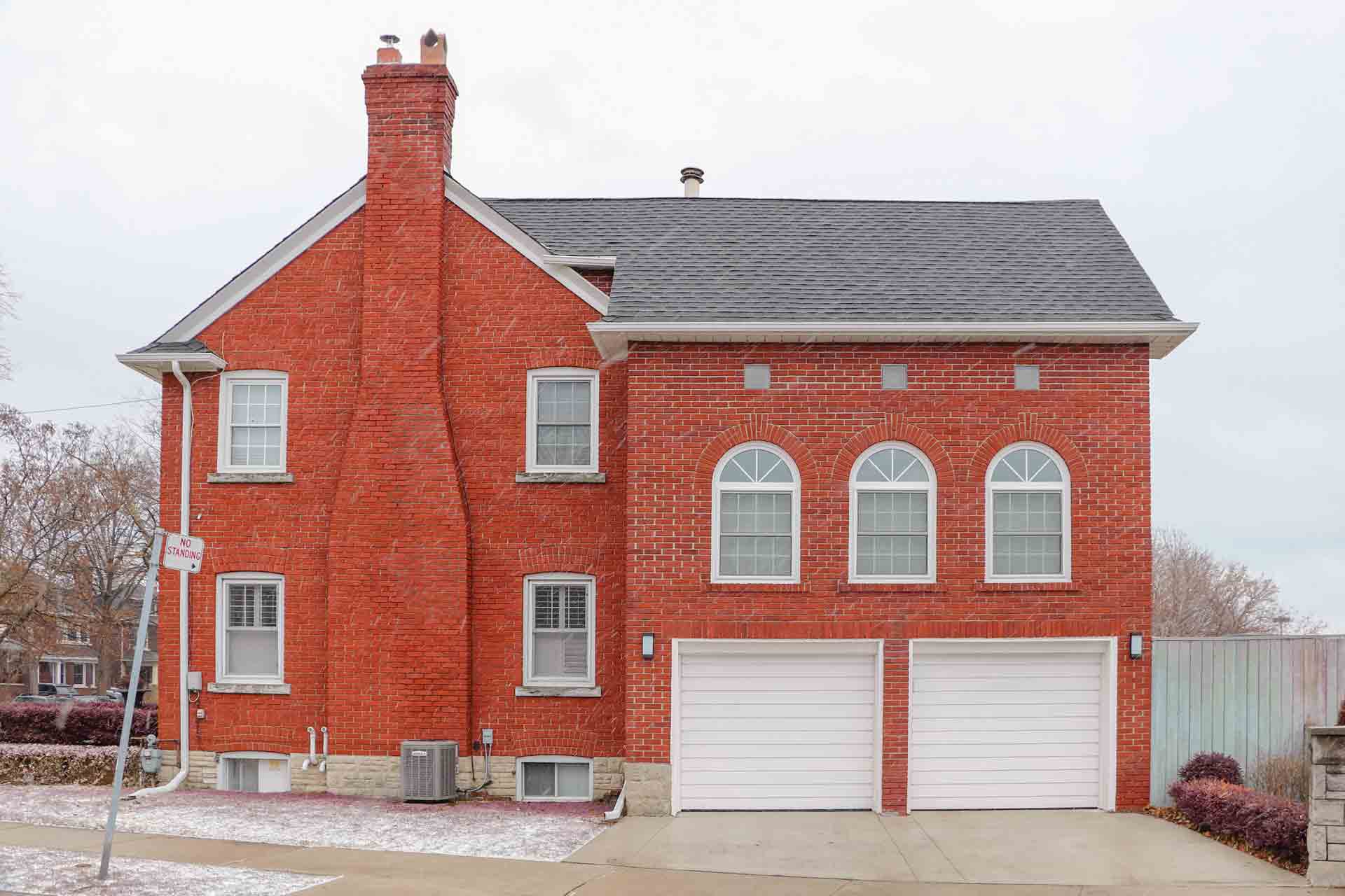 A large red brick house with white garage doors and arched windows best materials for garage doors Smart Garage Door Service