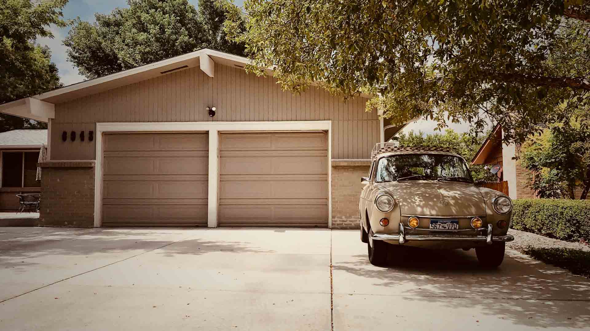 A car is parked in front of a house with two garage doors. carriage house garage doors Smart Garage Door Service