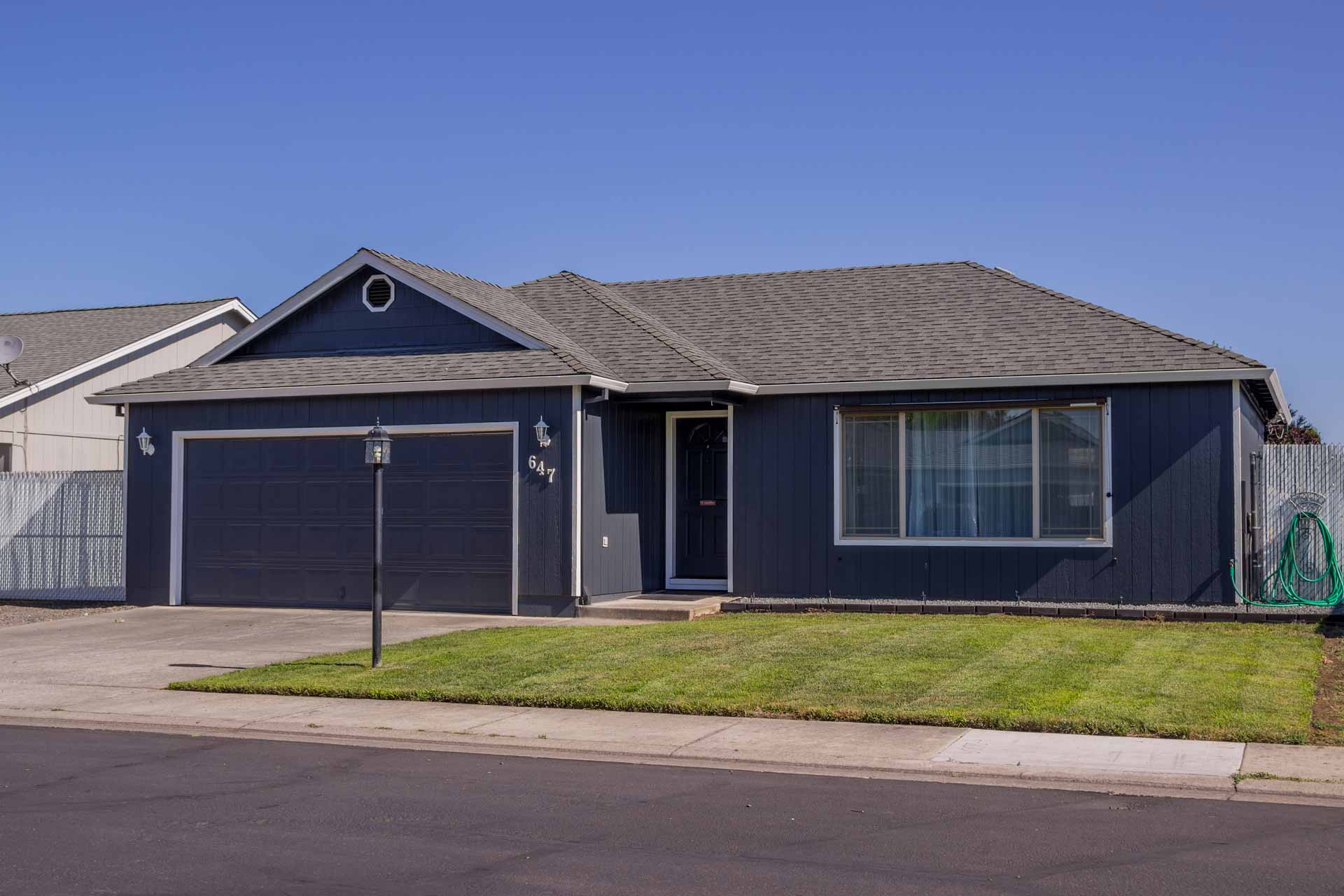 A house with a blue siding and a gray roof. Metal Garage Doors Smart Garage Door Service