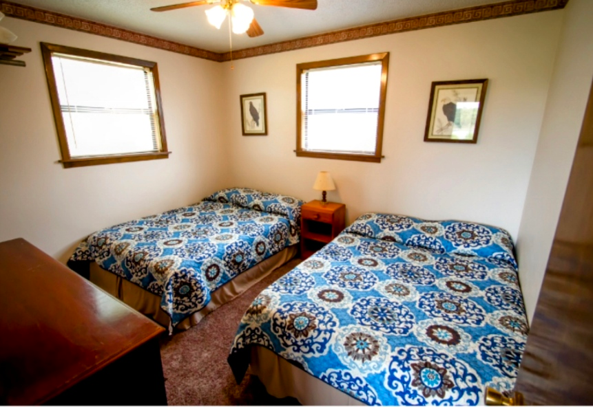 A bedroom with two beds and a ceiling fan