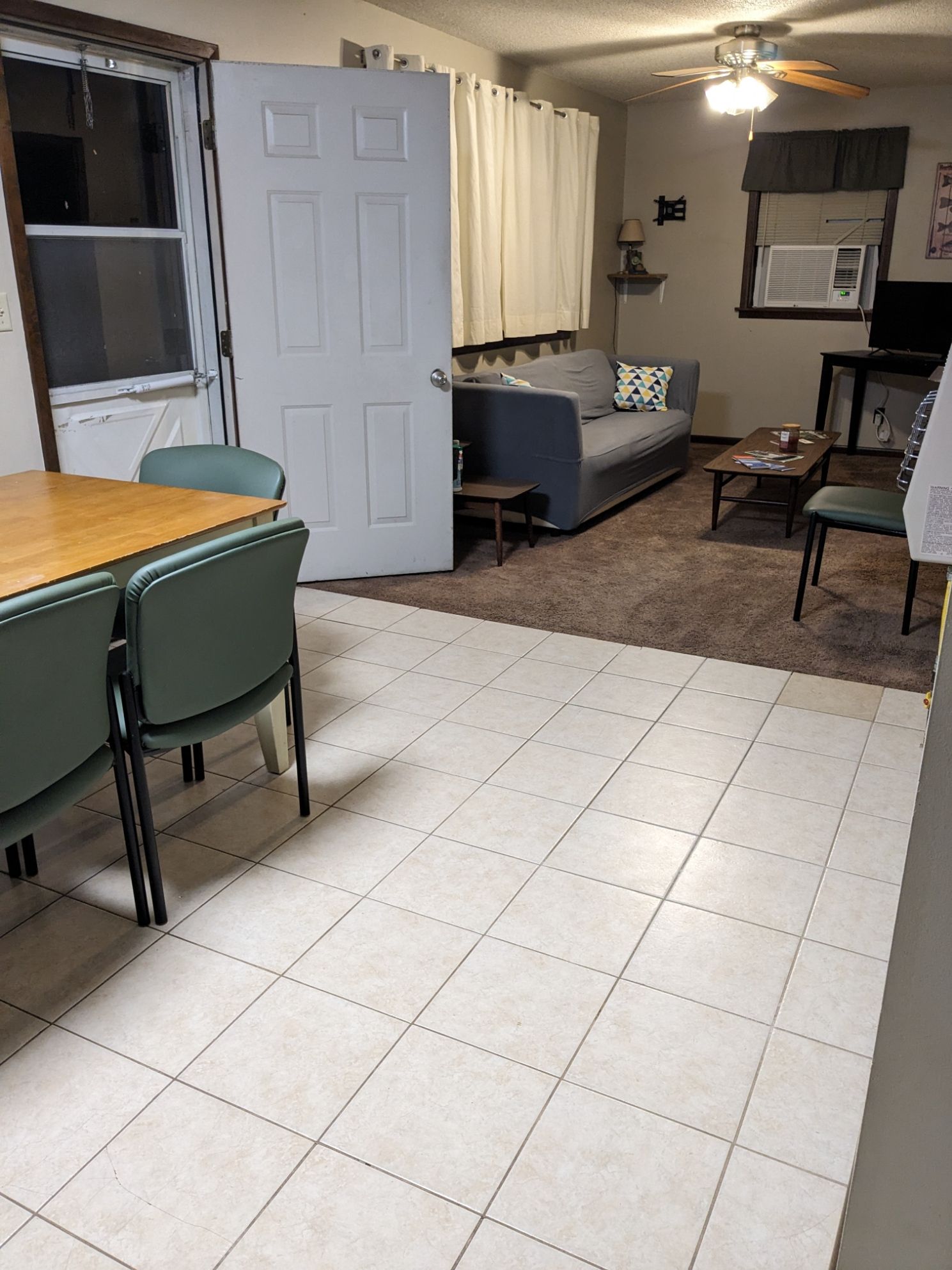 A living room with a couch , table , chairs and a ceiling fan.