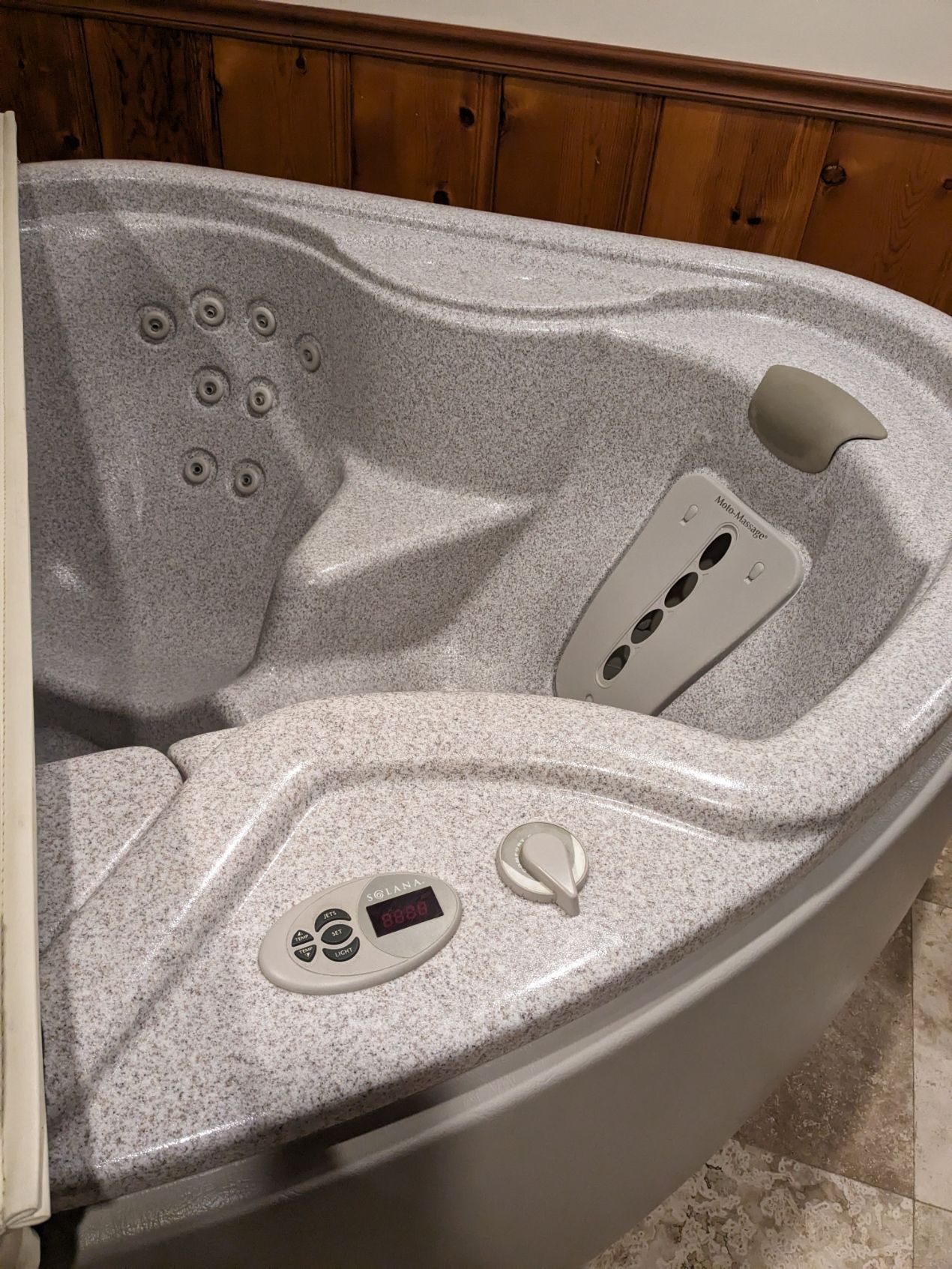 A hot tub is sitting in a bathroom next to a wooden wall.