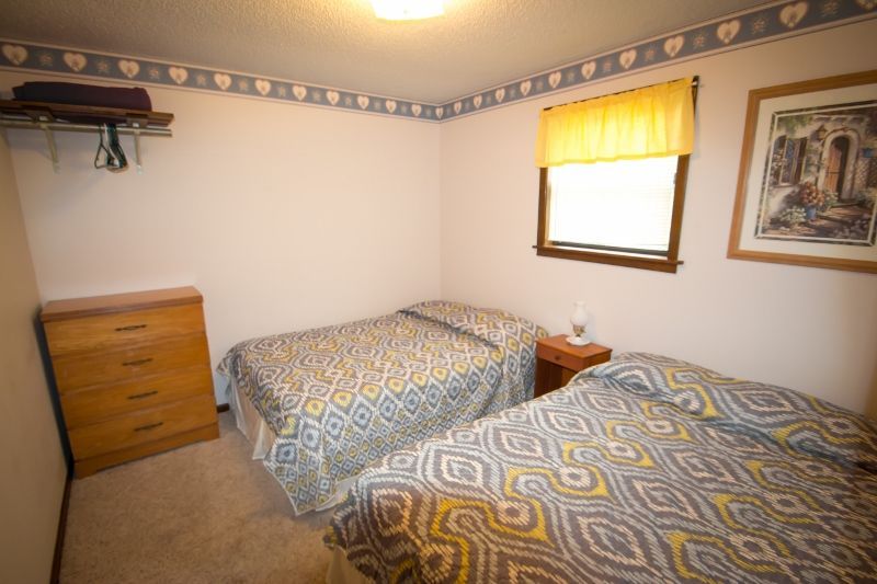 A bedroom with two beds , a dresser and a window.