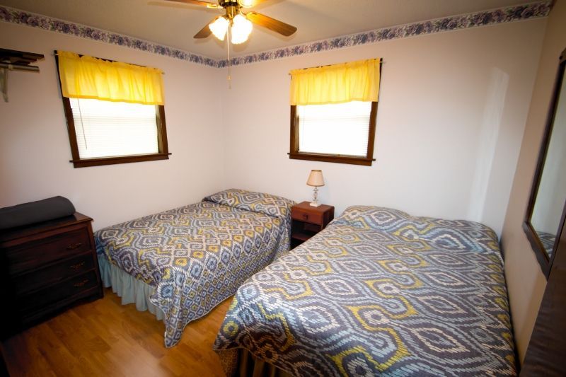 A bedroom with two beds and a ceiling fan.