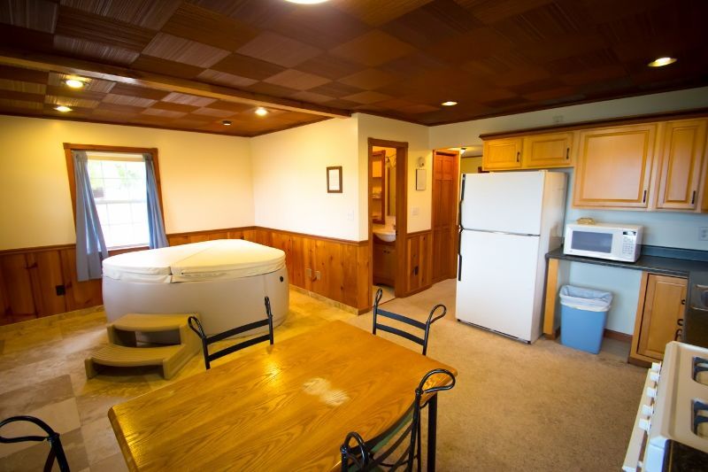 A kitchen with a table , chairs , refrigerator and microwave.