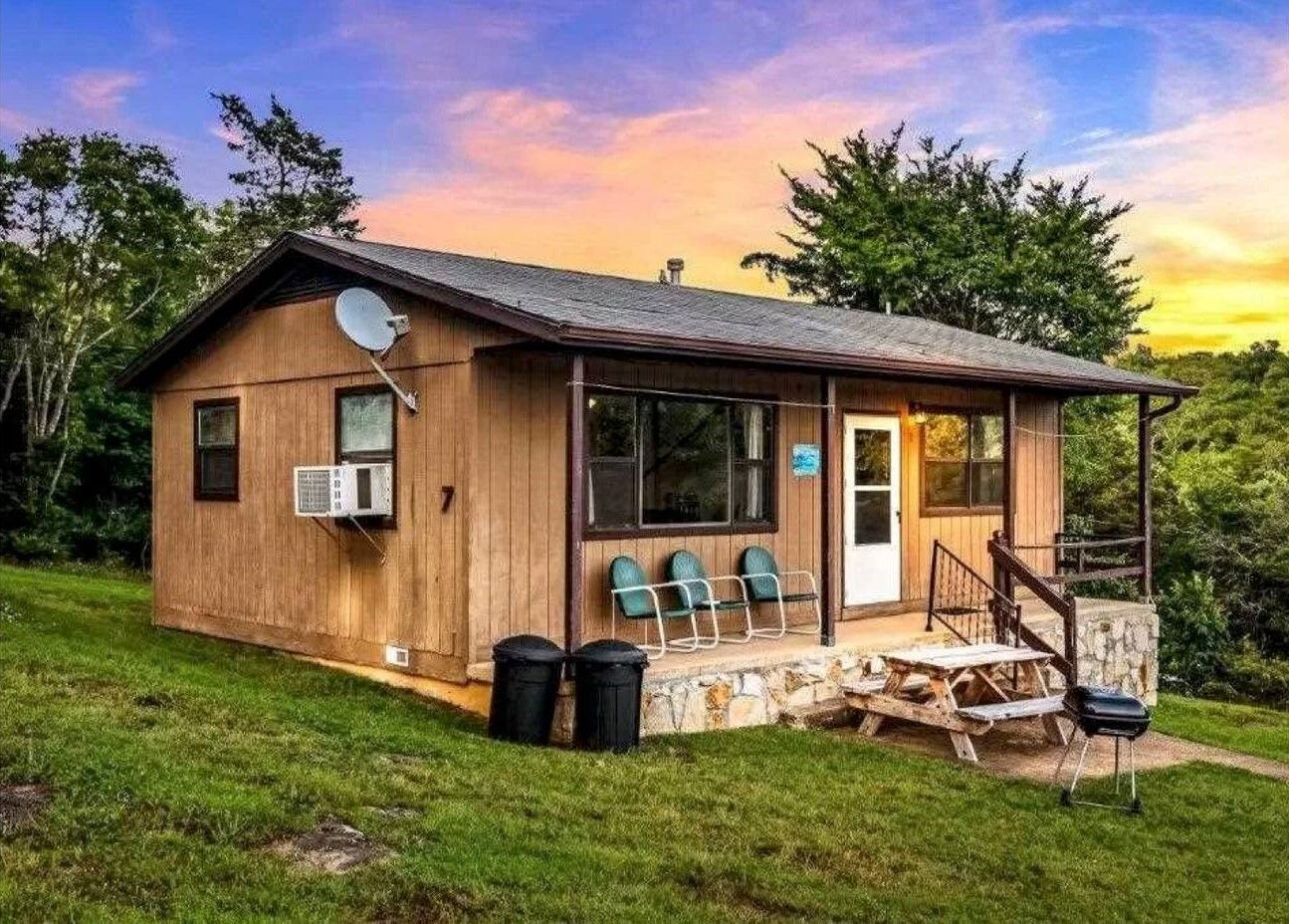 A small house with a porch and a picnic table in front of it.