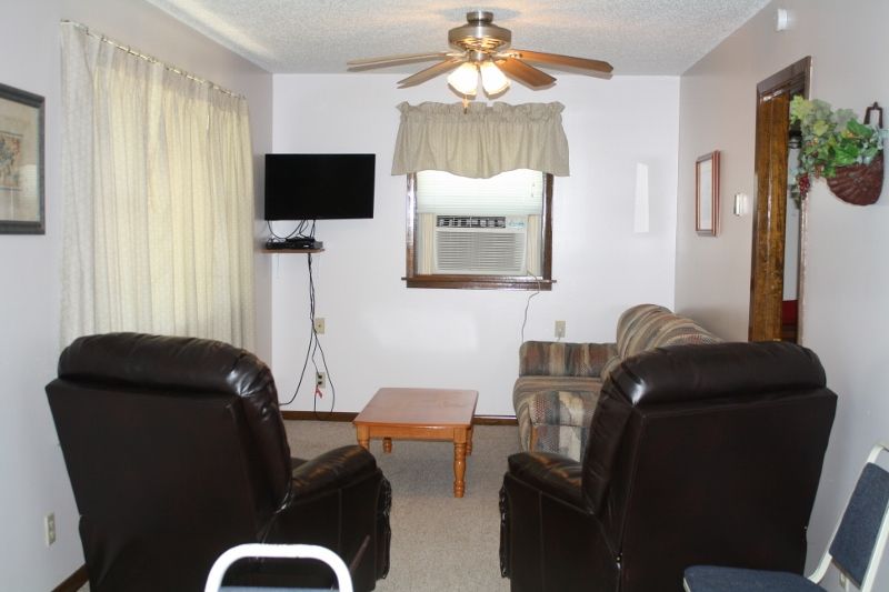 A living room with a ceiling fan and a flat screen tv