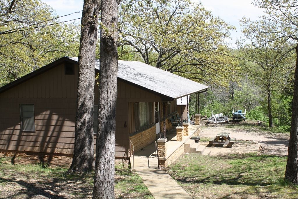 A house in the middle of a forest with trees in front of it