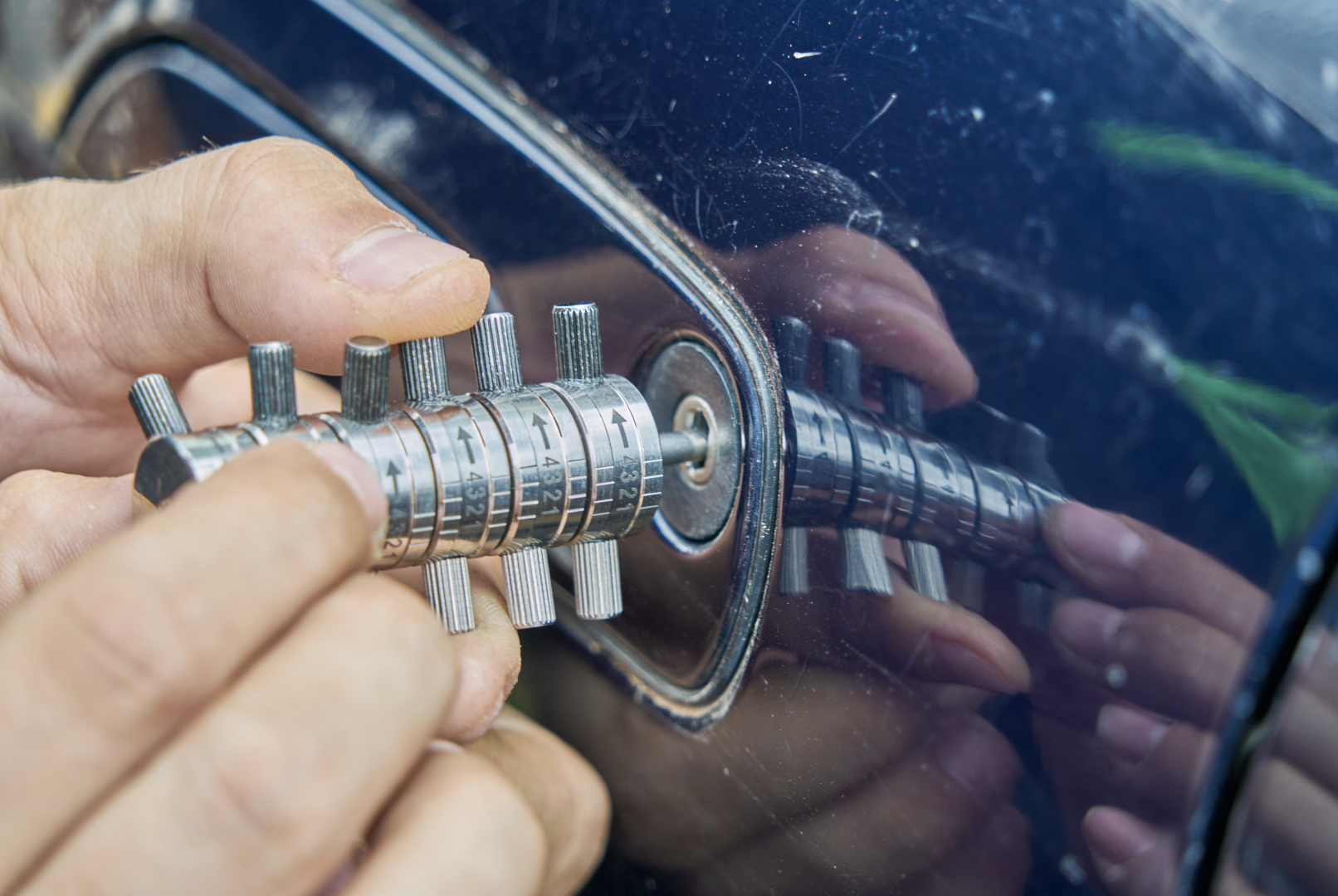 A person is trying to open a car door with a key.