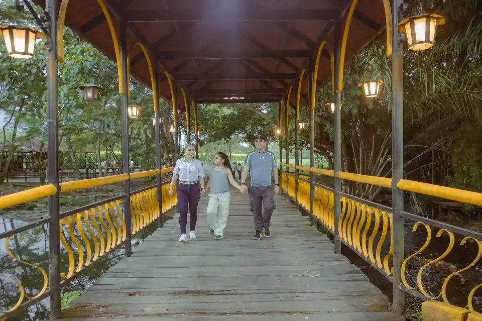 Pareja caminando por el puente amarillo de Hotel La Potra, plan romántico y natural cerca de Bogotá.