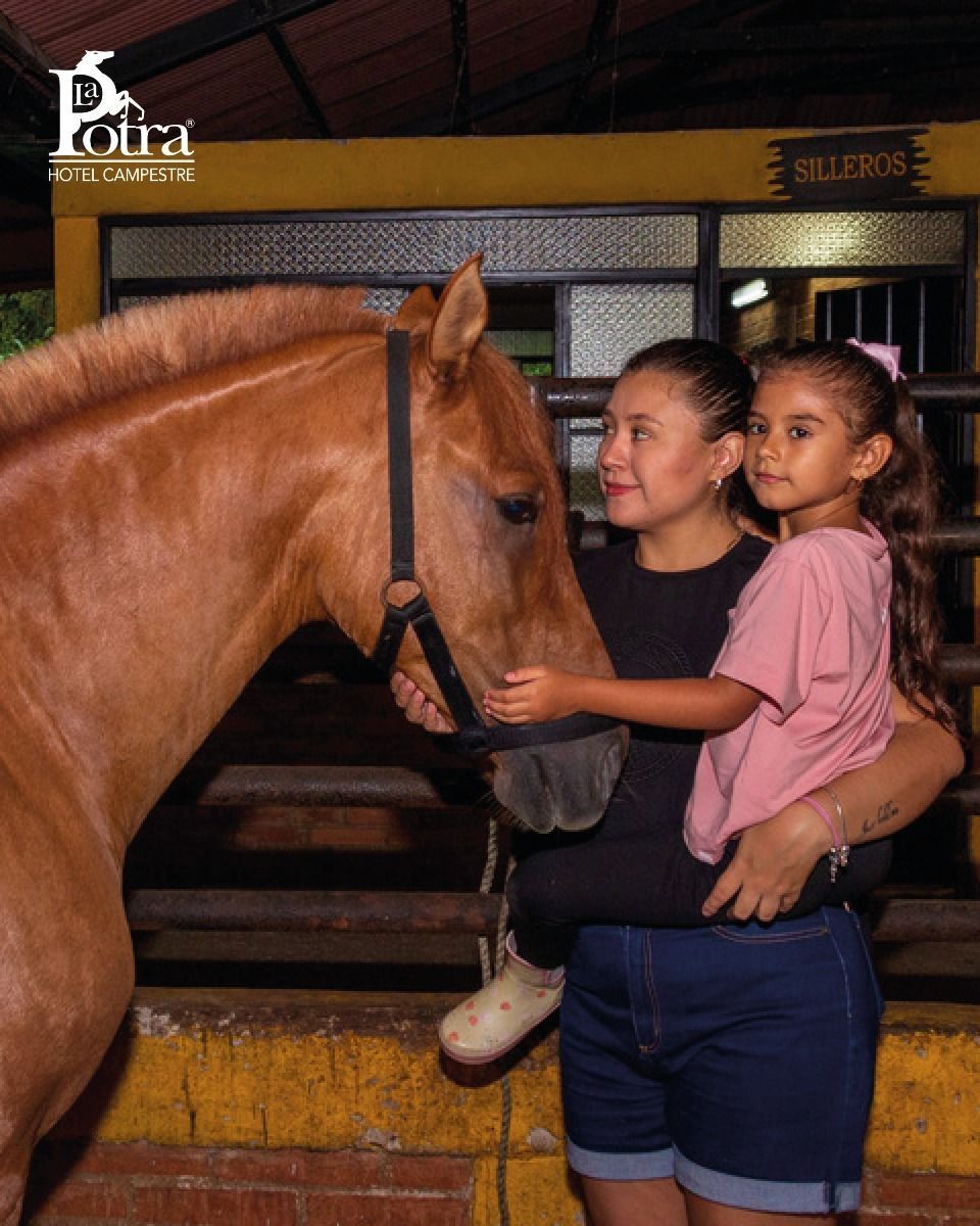 Niña acariciando un caballo en Hotel La Potra, experiencia rural para familias en Villavicencio.