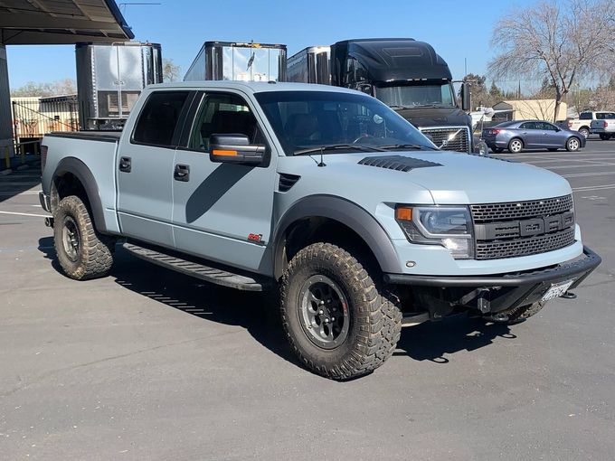 a gray ford raptor truck is parked in a parking lot .