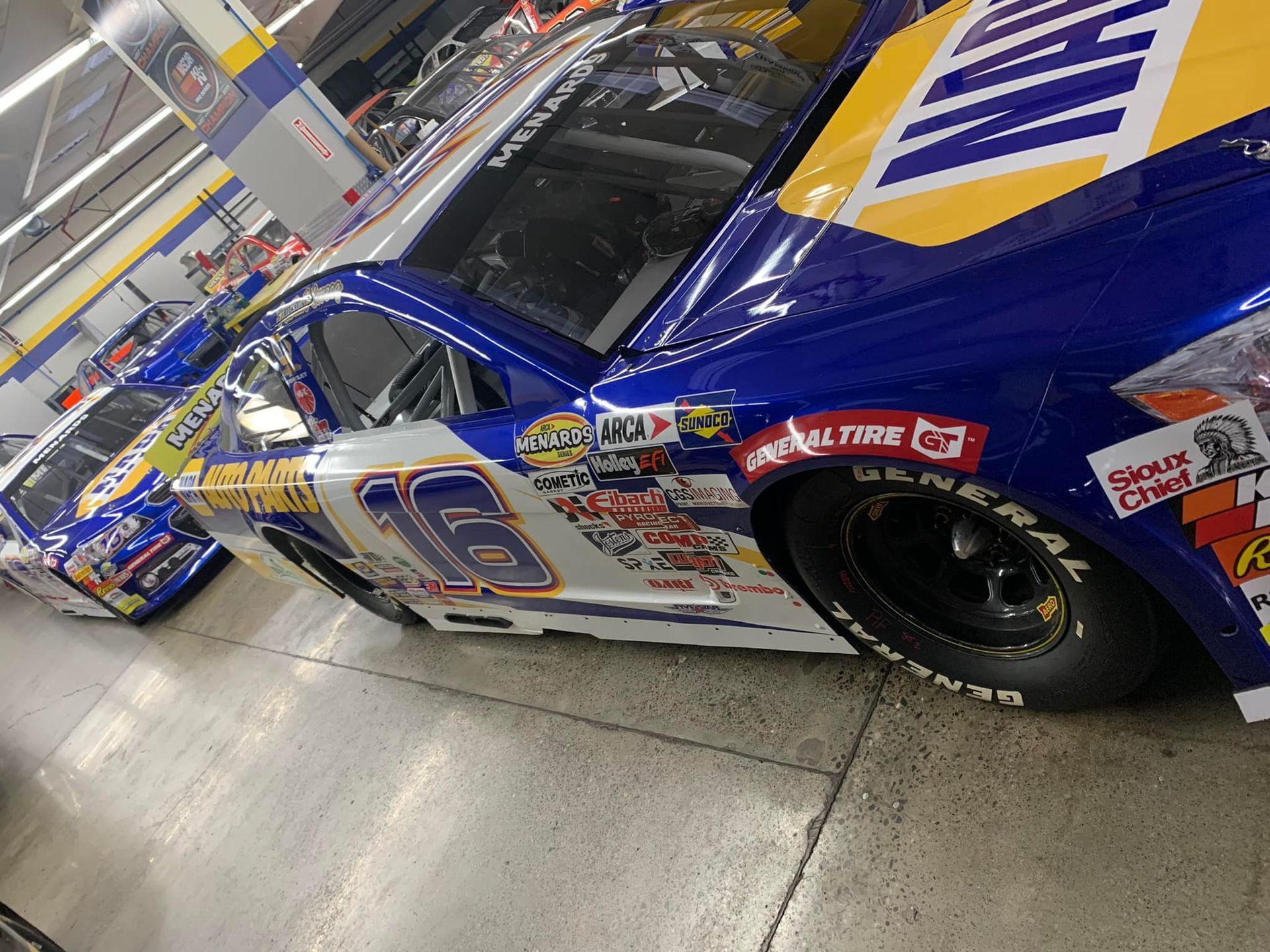 a race car with the number 16 on the side is parked in a garage .