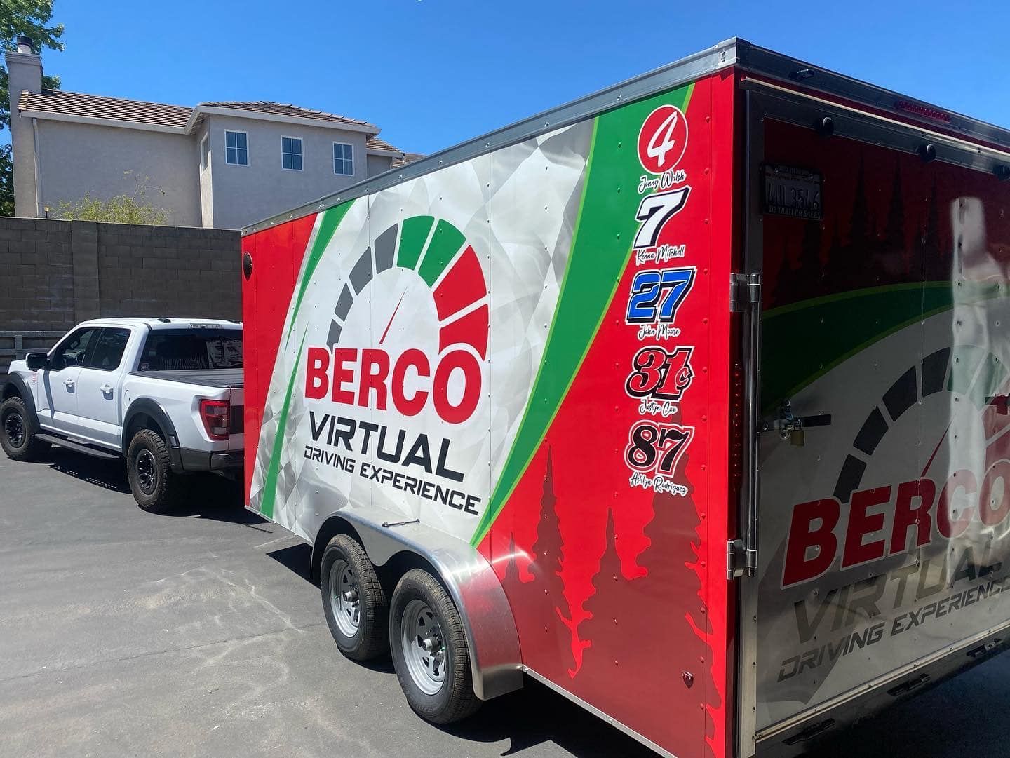 a white truck is towing a red and green trailer .