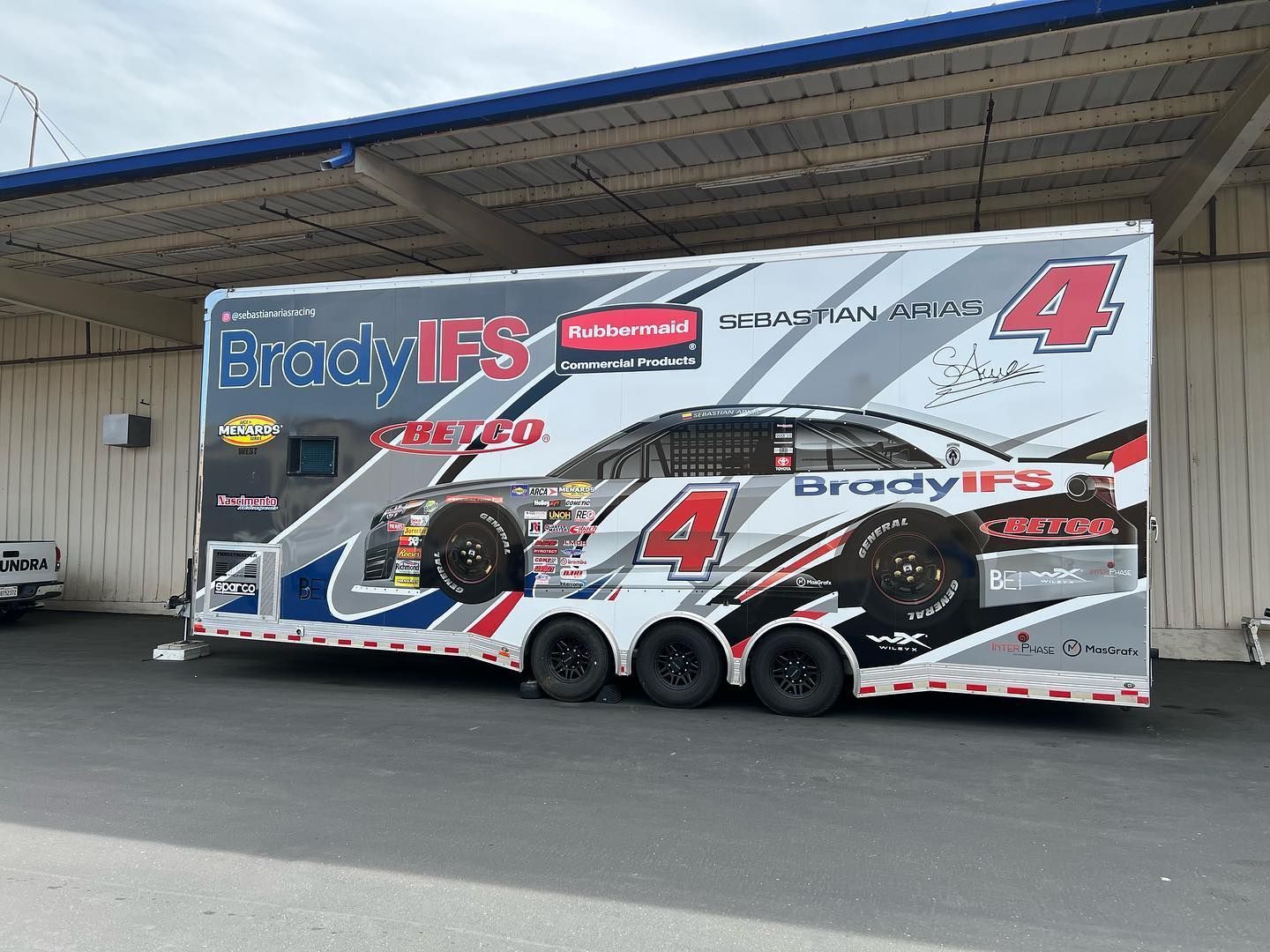 a race car trailer is parked in front of a building .