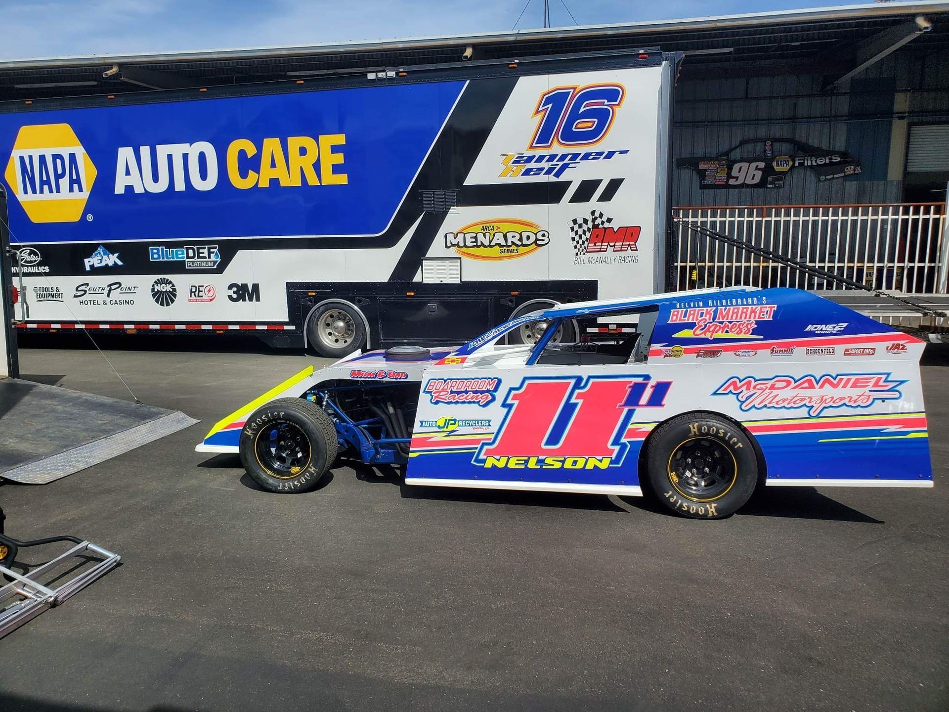 a race car is parked in front of a napa auto care truck