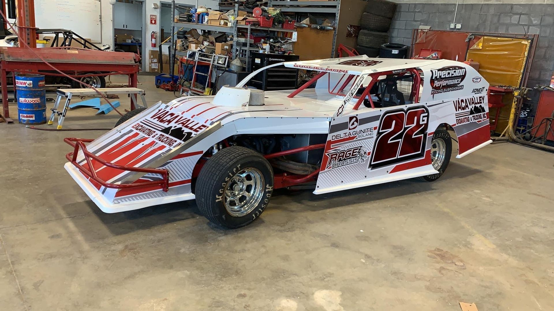 a red and white race car is parked in a garage .