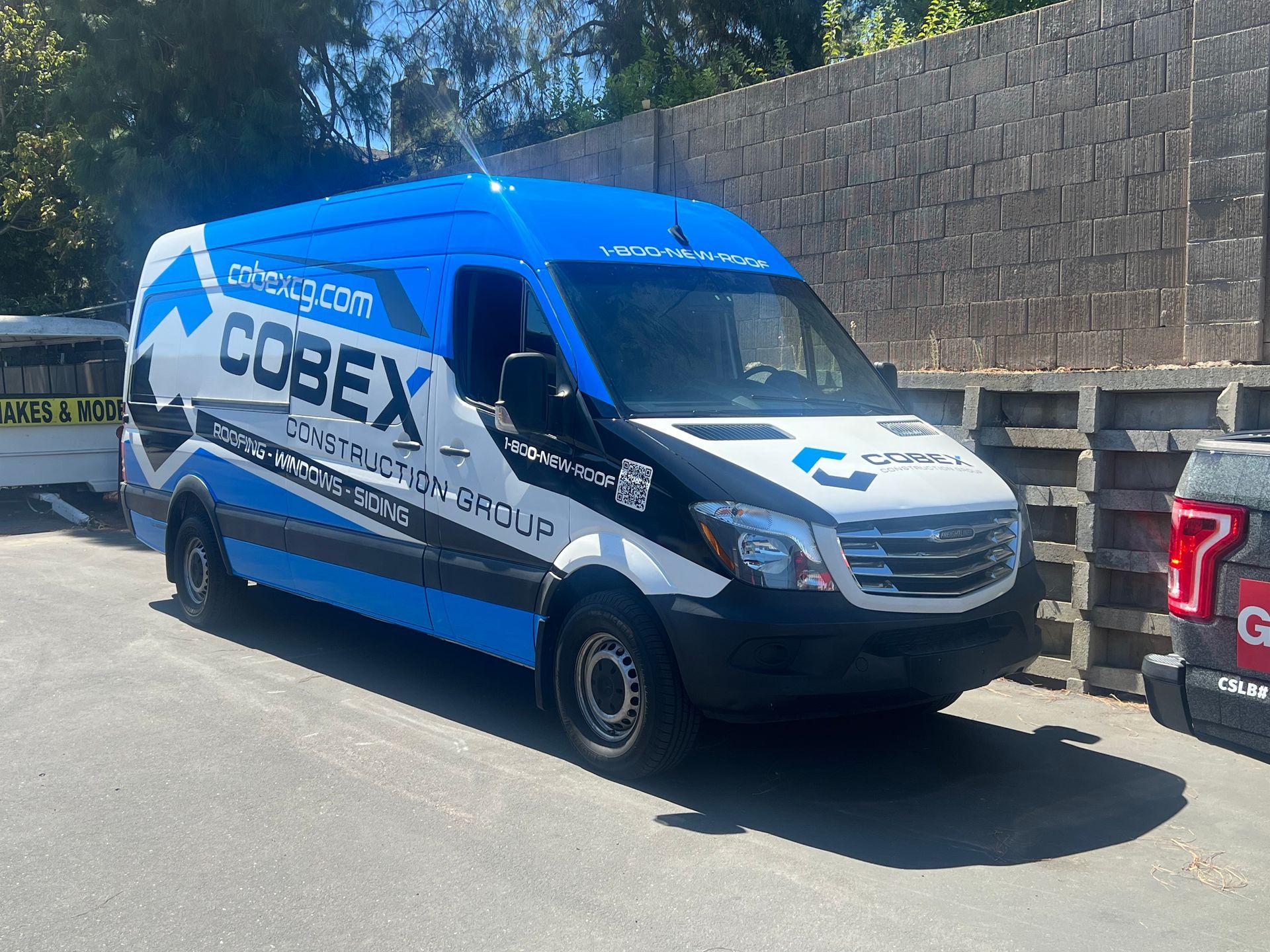 a blue and white van is parked in front of a brick wall .