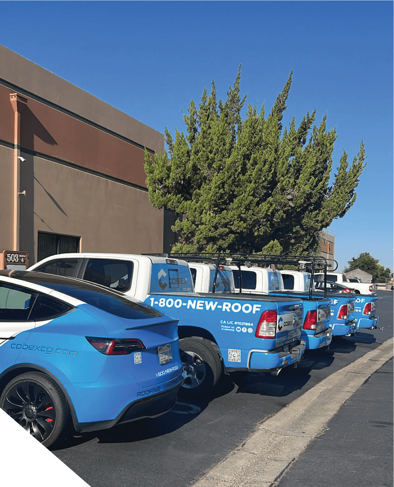 A row of blue cars parked in front of a building