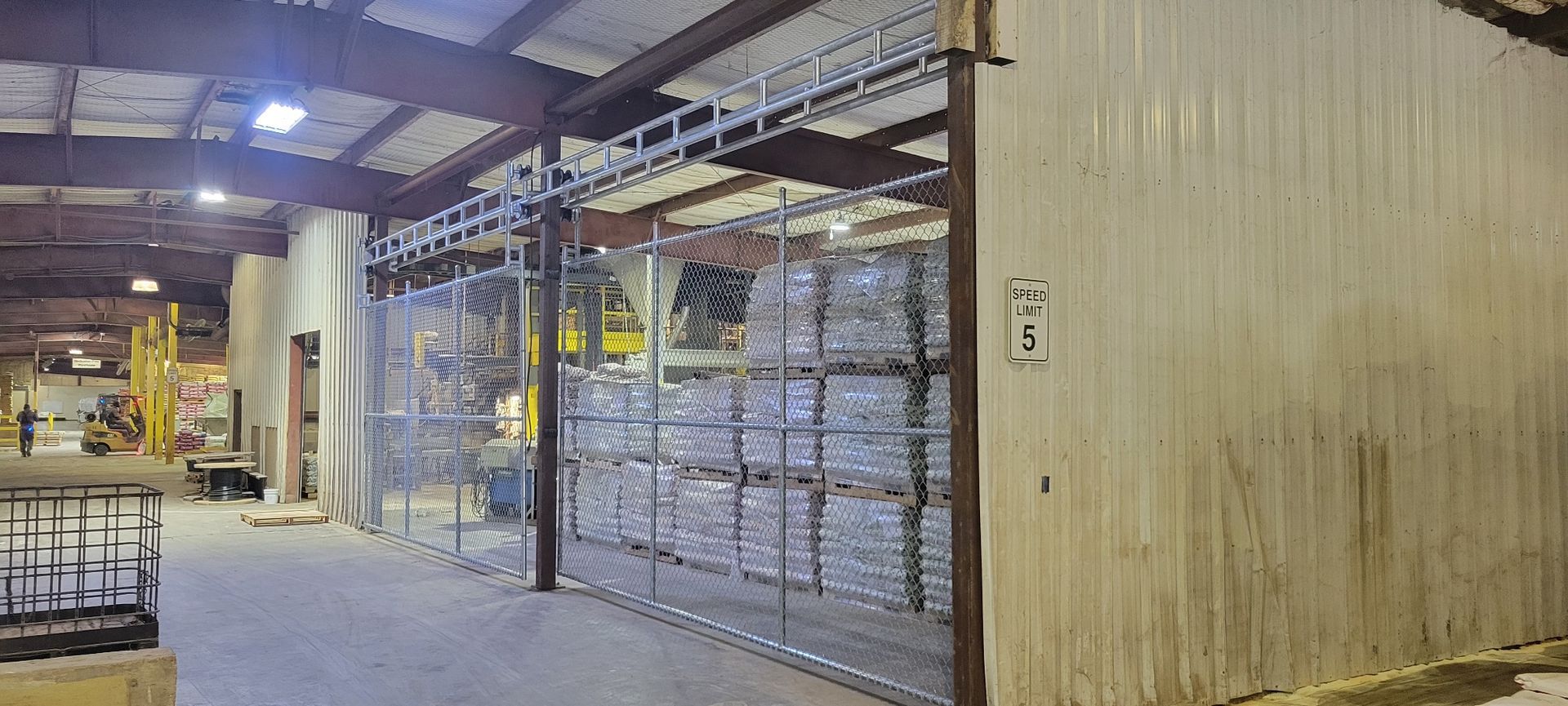 A large warehouse with lots of shelves and a fence.
