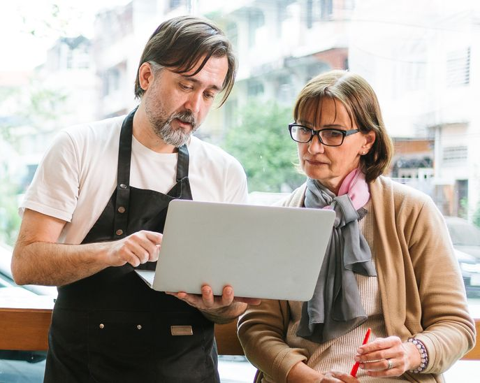 A woman reviews documents with a couple at a table, likely a business meeting.