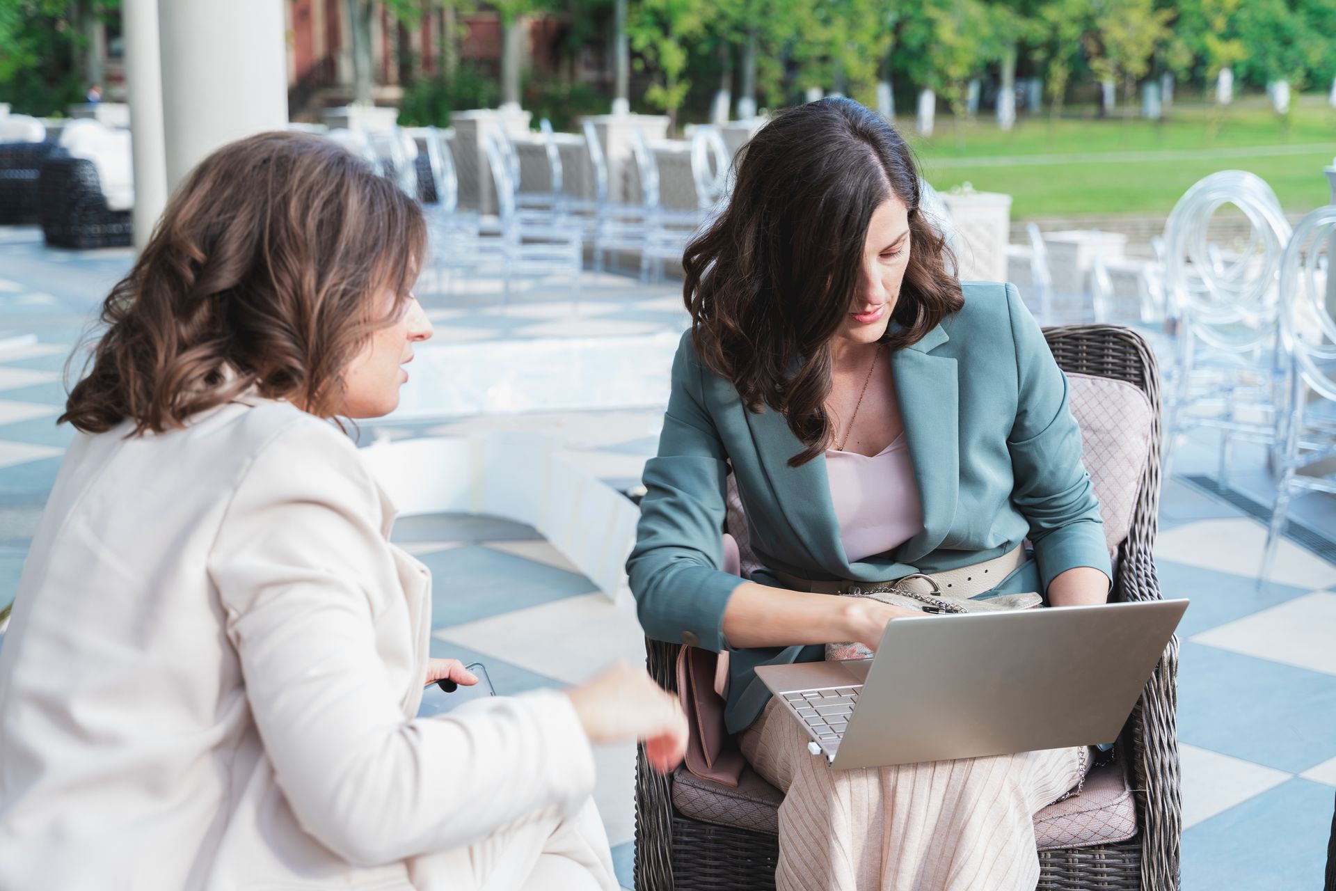 Group of people in business attire at a conference table, reviewing documents and using laptops. Modern office setting.