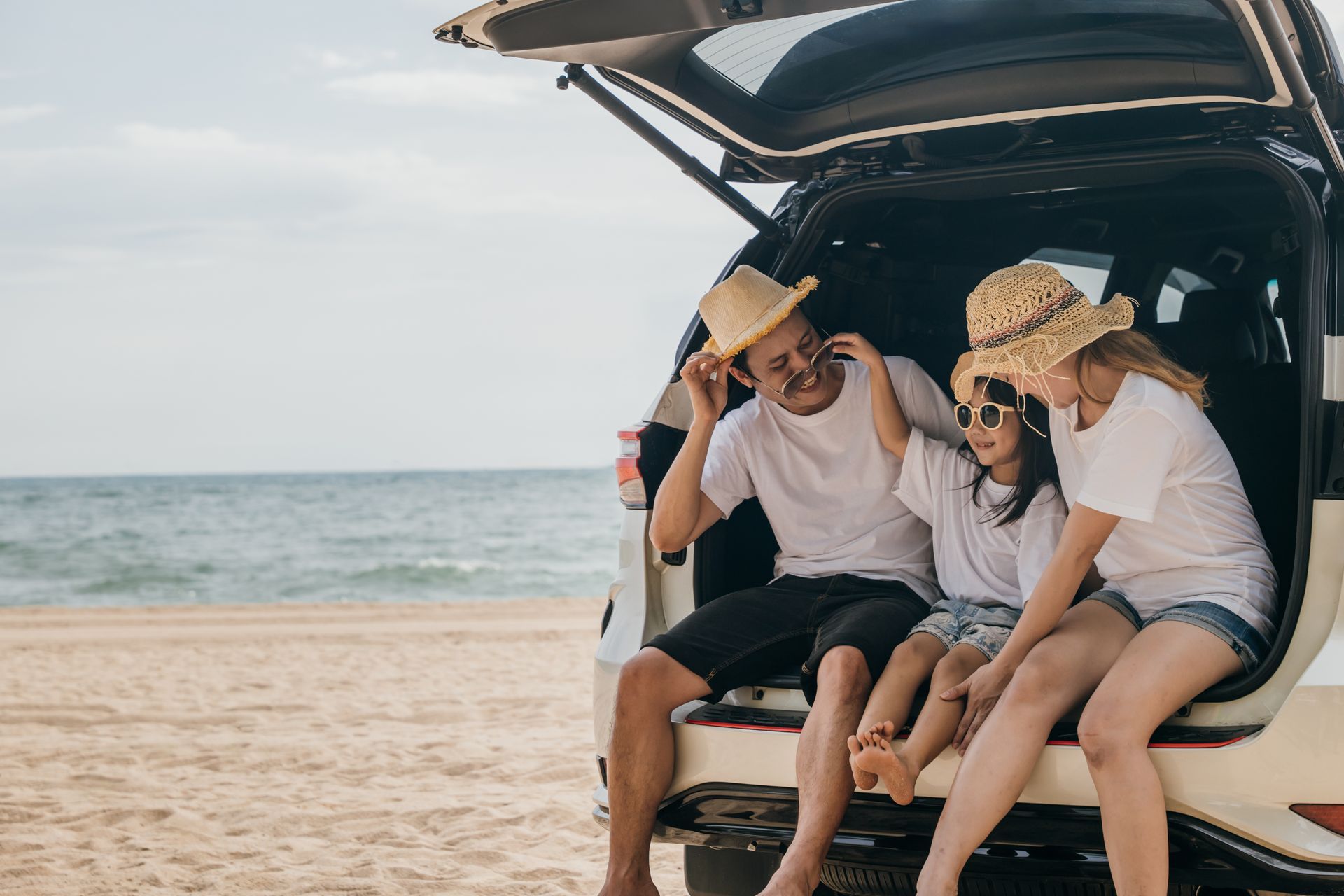 Family makes a home with arms: parents with a child smiling on a rug in a living room.
