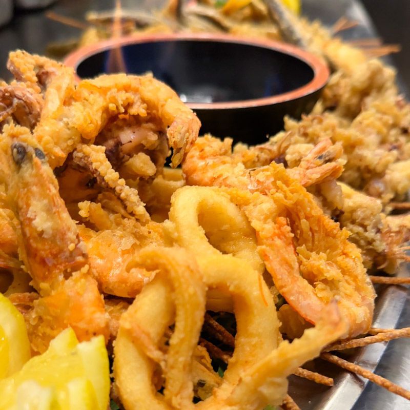 Piatto di pesce fritto: gamberi, calamari e altre prelibatezze fritte con salsa.