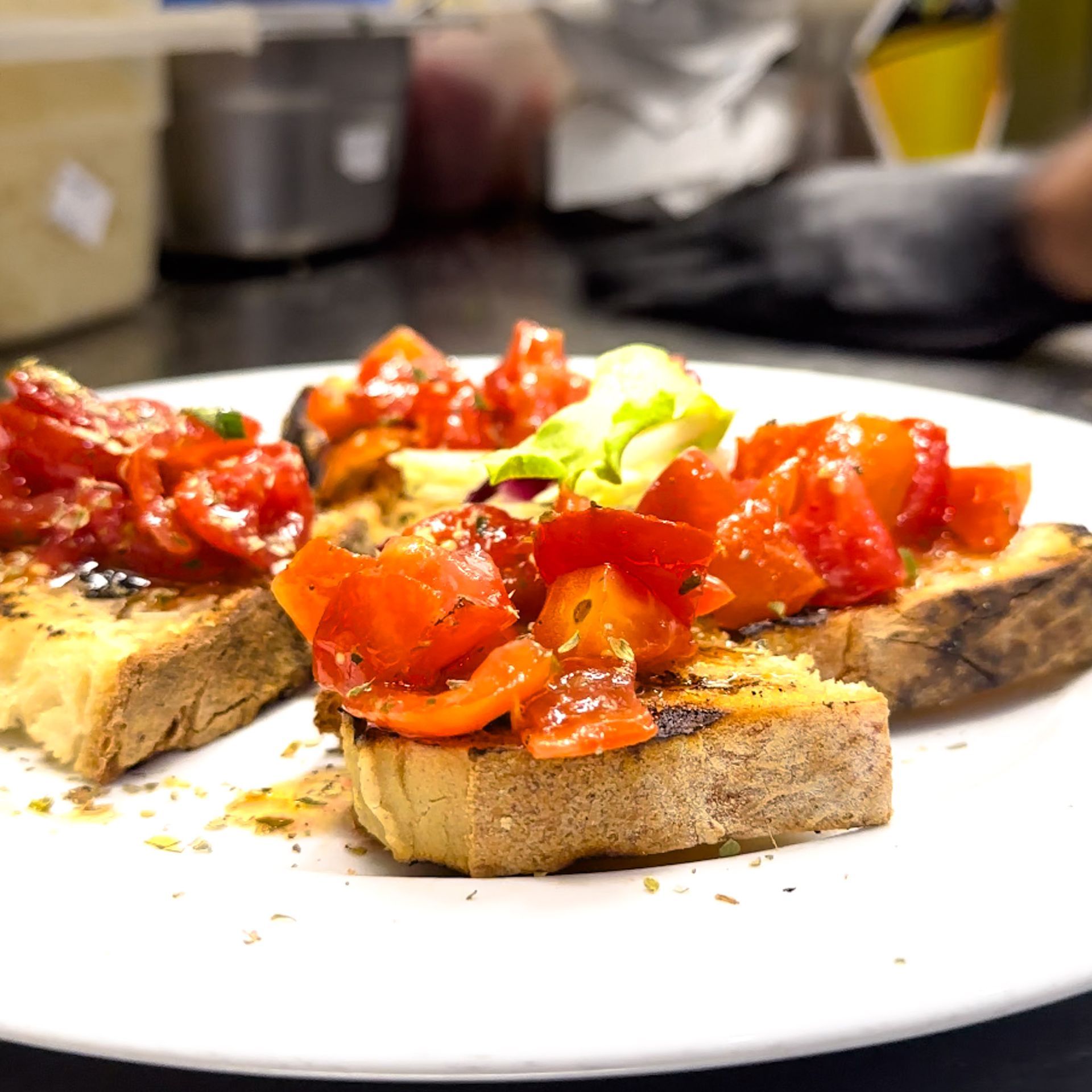 Antipasto di bruschetta: pane tostato condito con pomodori rossi e peperoni a cubetti, servito con verdure.
