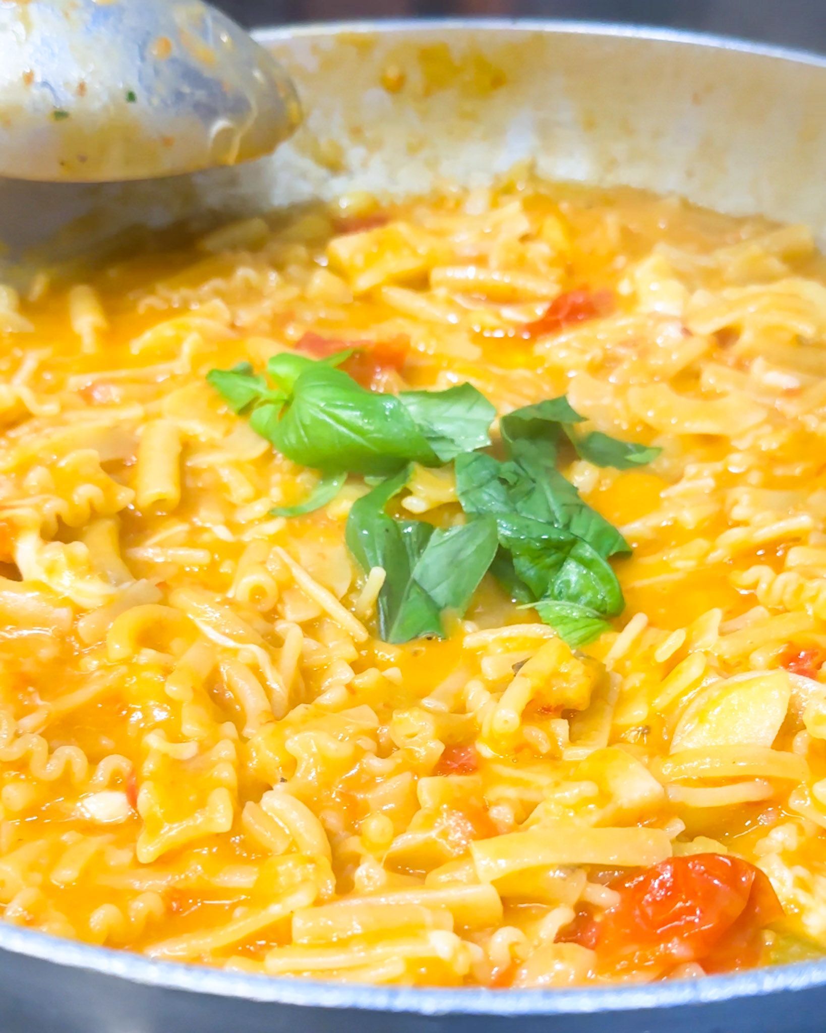 Piatto di pasta con salsa di pomodoro e guarnizione di basilico.