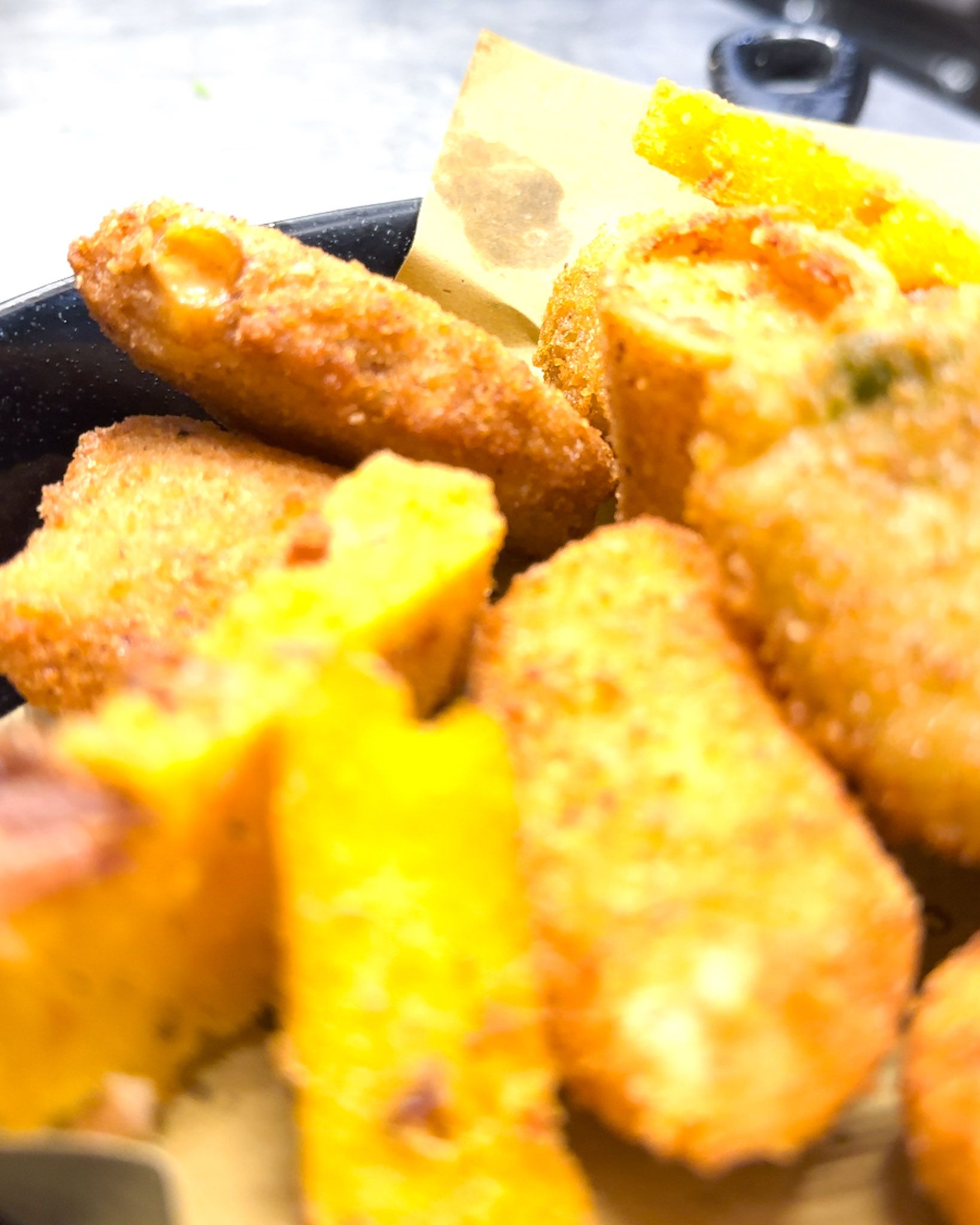 Primo piano di un piatto con vari tipi di cibo fritto dorato.