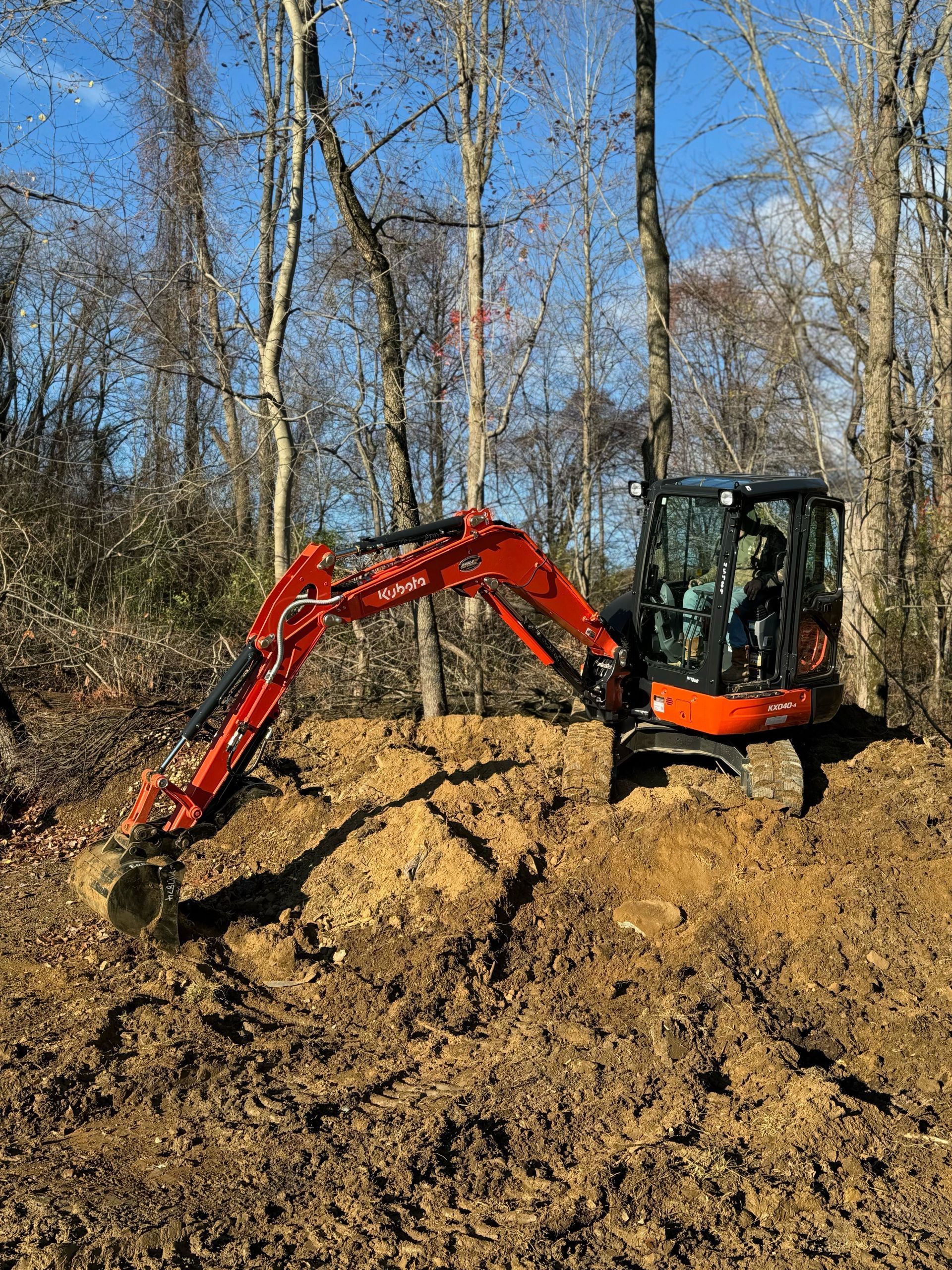 A red and orange excavator is sitting in the middle of a dirt field.