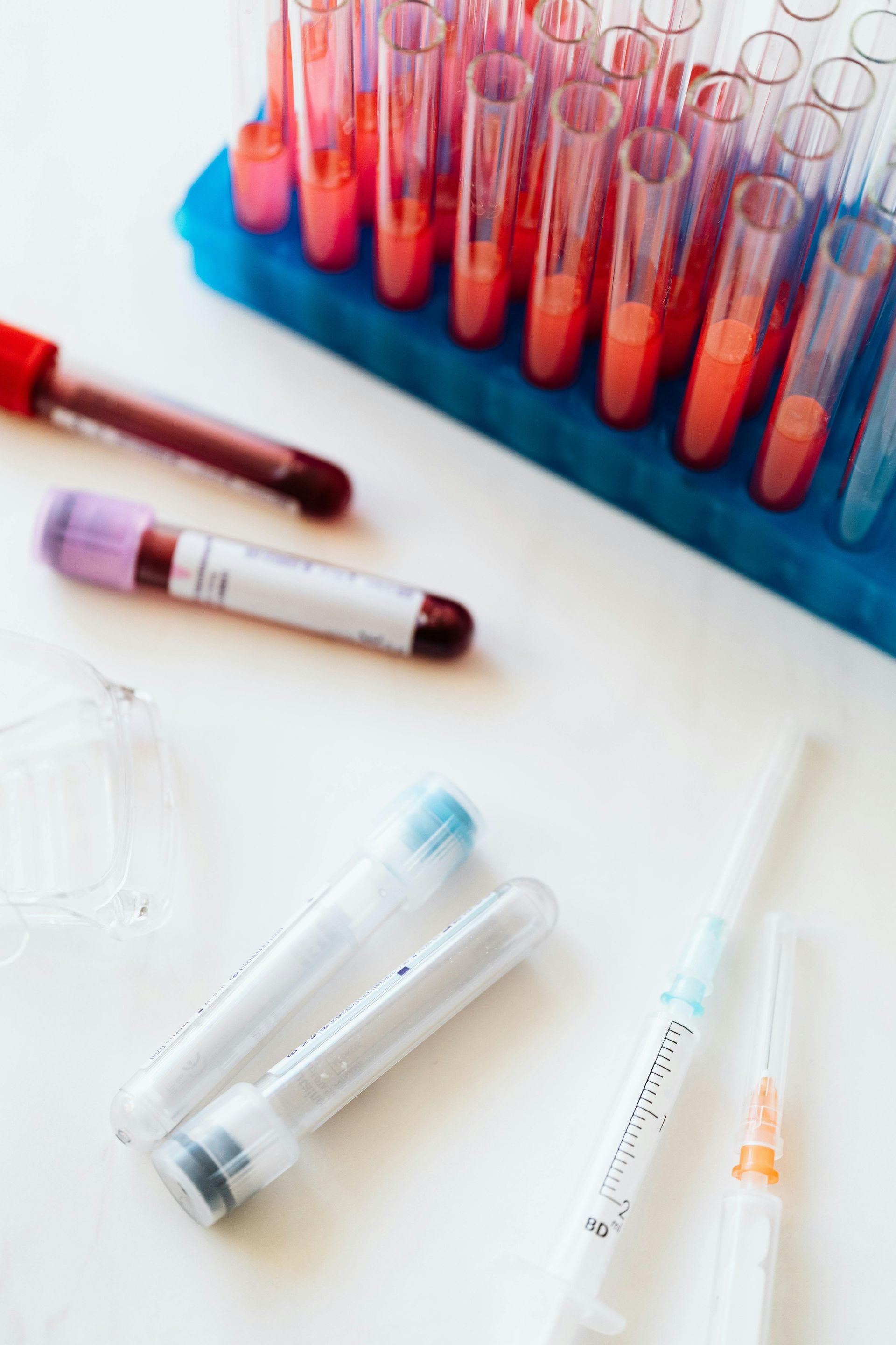 Blood samples in vials and a syringe on a white surface, likely in a lab setting.