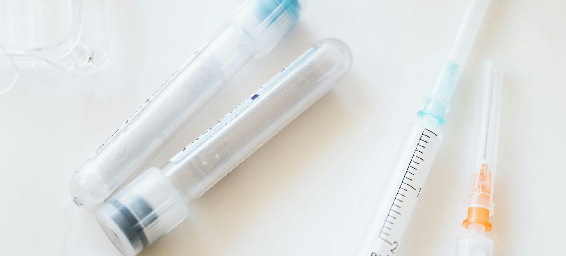 Medical equipment on a white surface, including test tubes and syringes.