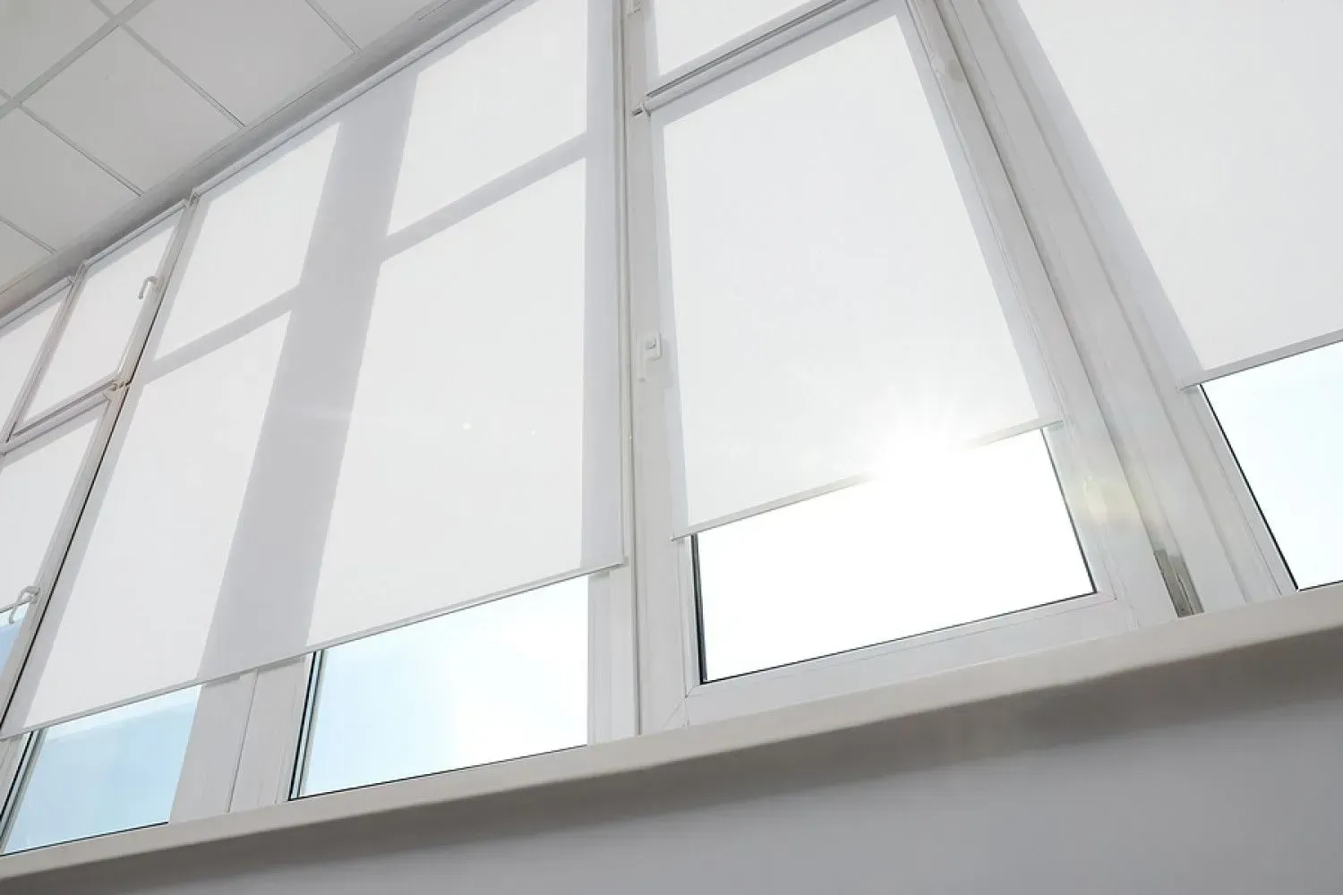 The sun is shining through the blinds on the windows.