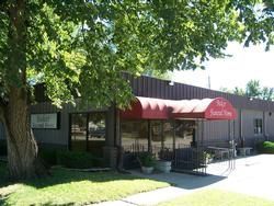 Funeral home building with red awning, large windows, and a grassy lawn.