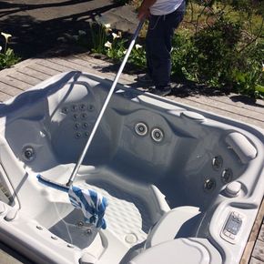 A man is cleaning a hot tub with a mop