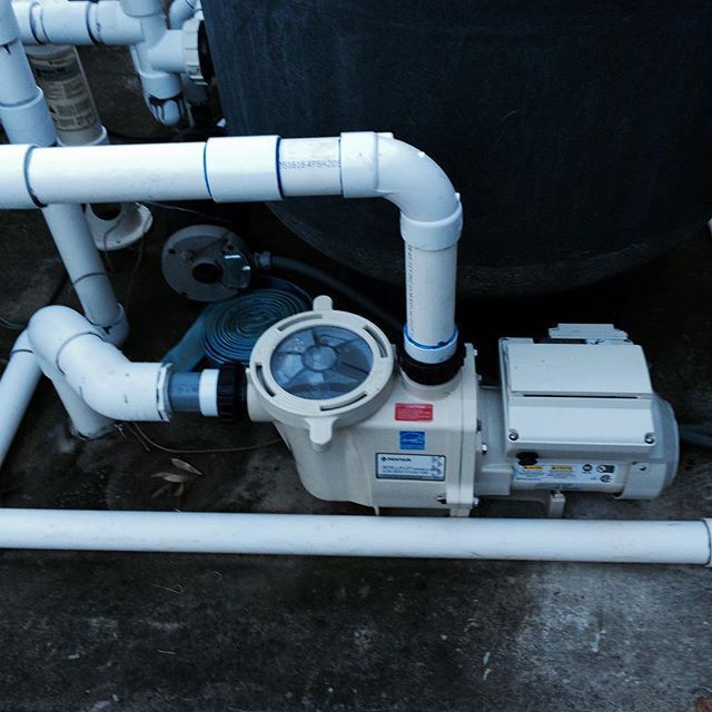 A swimming pool pump is attached to a white pipe