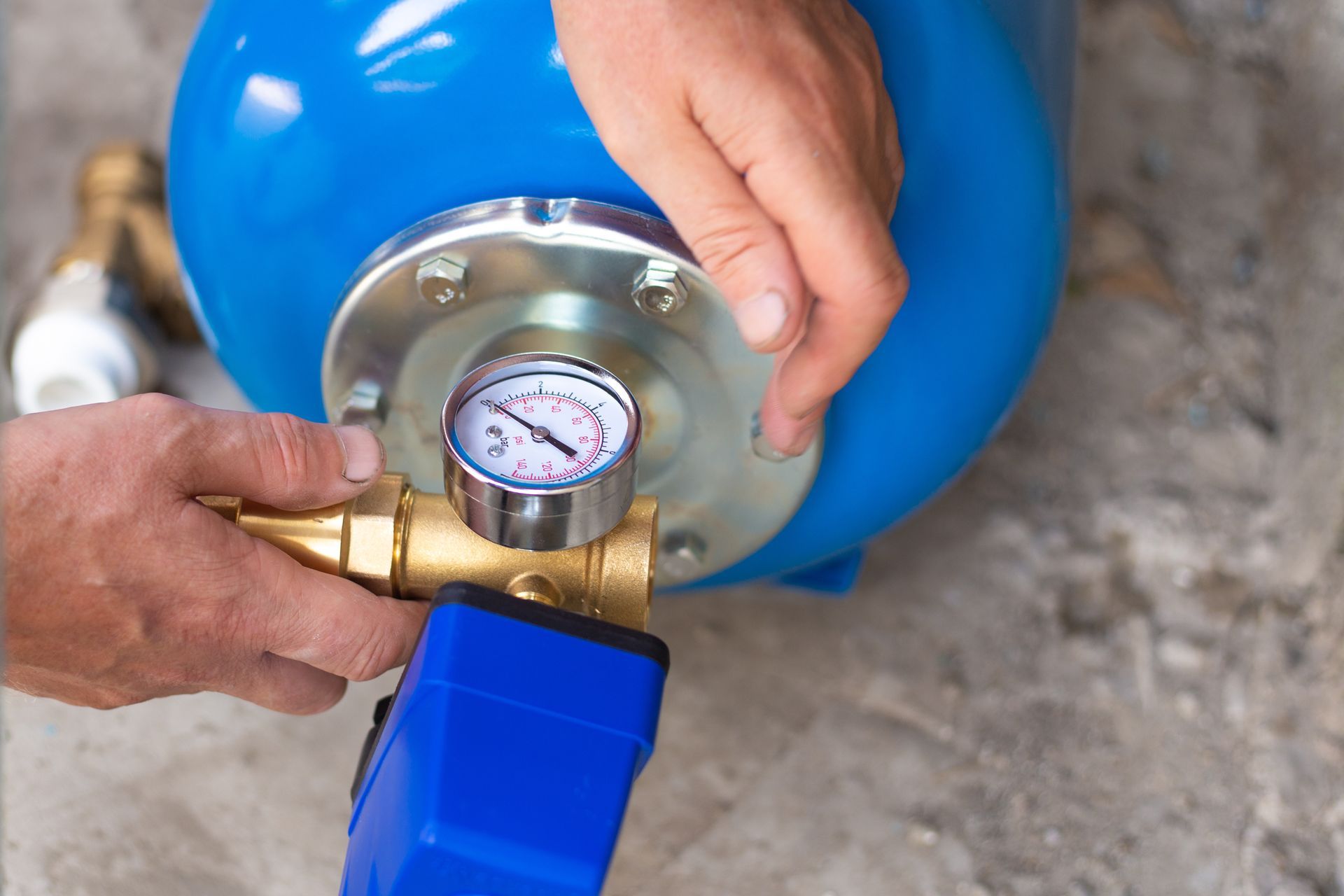 Hands holding a blue pressure tank with an attached pressure gauge and brass fittings. Hands holding a blue pressure tank with an attached pressure gauge and brass fittings.