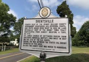 A historical marker for Brentsville, Prince William County, standing on a grassy roadside under a blue sky.