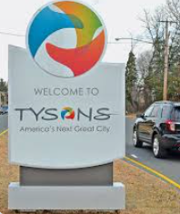 A Tysons, Virginia, welcome sign features a colorful abstract logo and the slogan America's Next Great City by a road. A Tysons, Virginia, welcome sign features a colorful abstract logo and the slogan America's Next Great City by a road.
