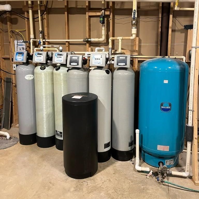 Water filtration system with multiple tanks and connected pipes in a basement.