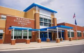 Waxpool Elementary School entrance with brick facade, blue awnings, and flagpole outside.