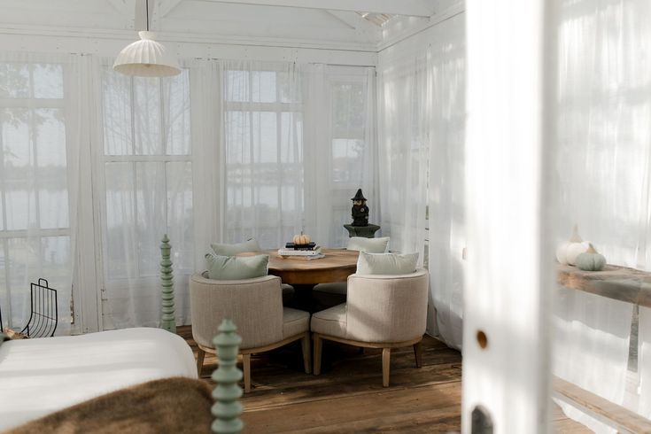 Deux chaises texturées font face à une table ronde avec des fleurs dans un vase, dans un patio clos et ensoleillé.