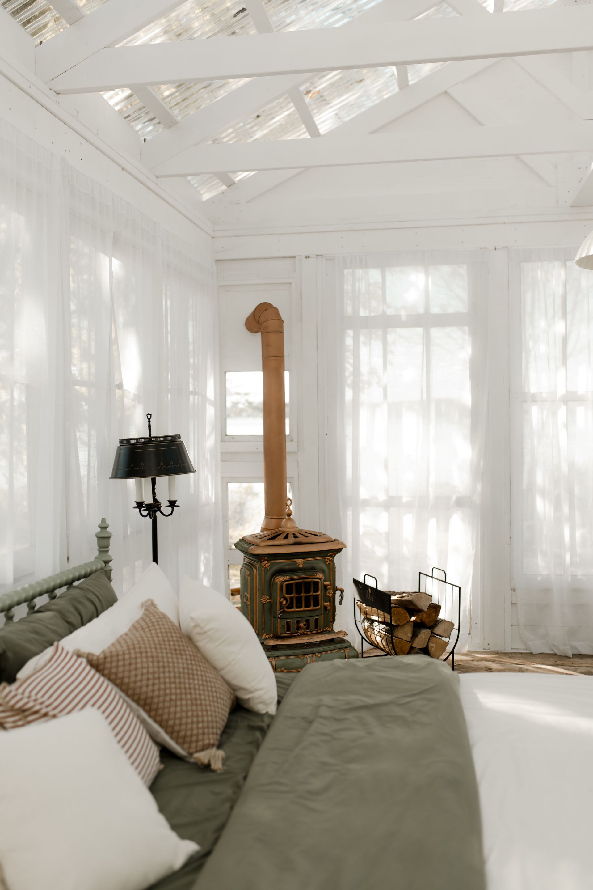 Deux chaises texturées font face à une table ronde avec des fleurs dans un vase, dans un patio clos et ensoleillé.